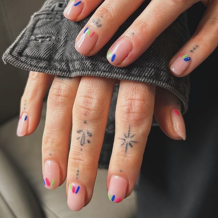 Natürliche Nägel mit zarten, bunten Farbakzenten in Pink, Blau und Grün an den Nagelspitzen.