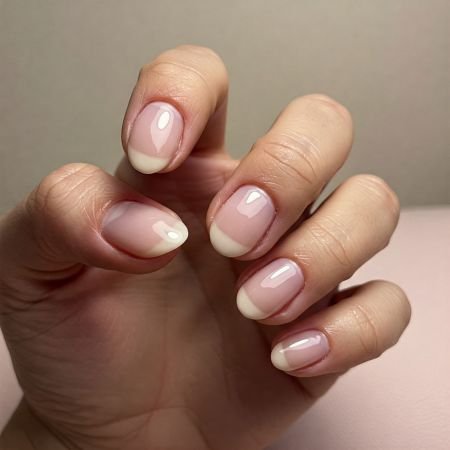 Eine Hand mit fünf Fingern, die glänzende, glatte Gel-Nägel mit natürlichem Look zeigt.